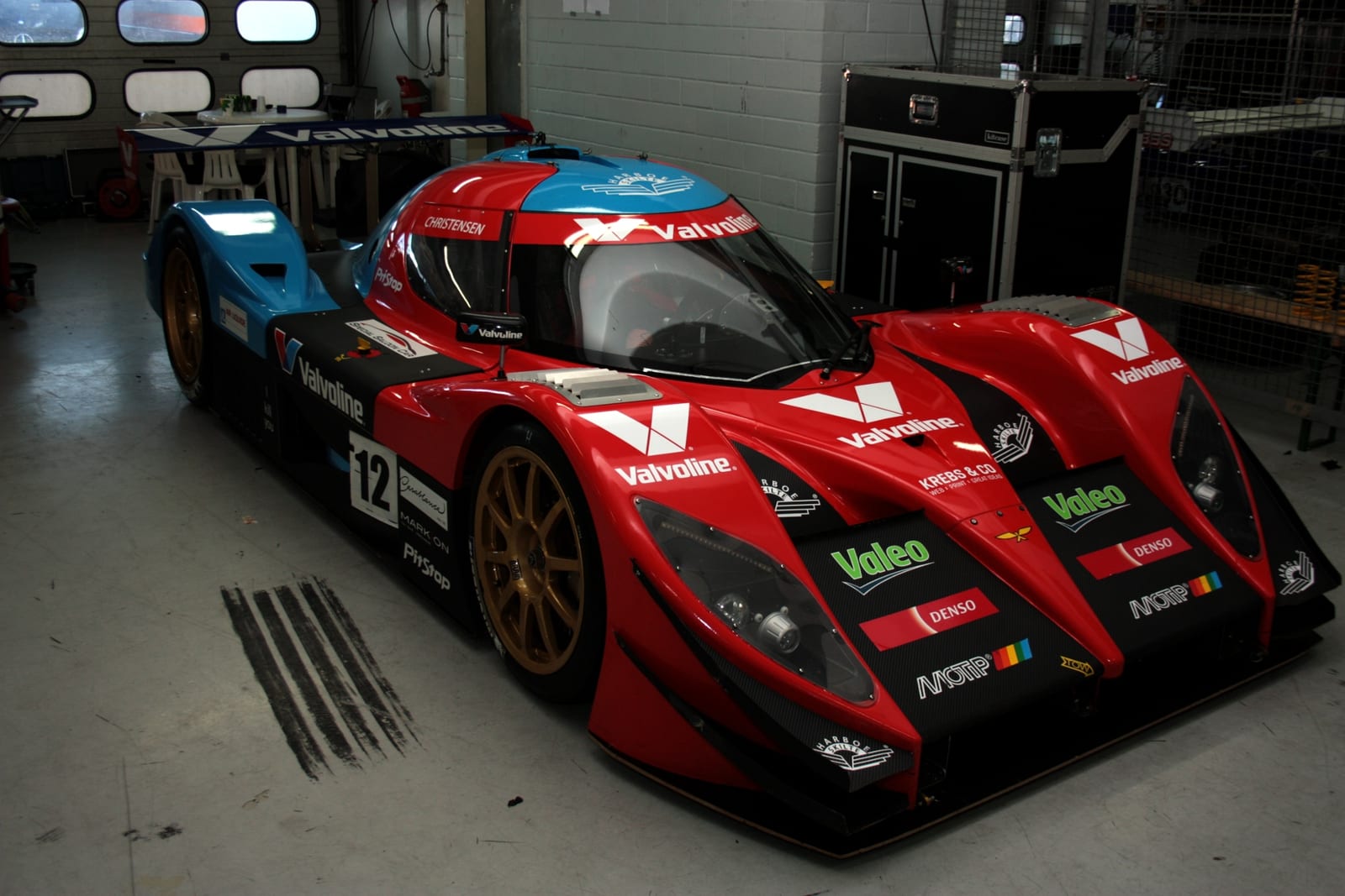 A red and blue Aquila CR1 Sports GT in a pit garage at Hockenheim