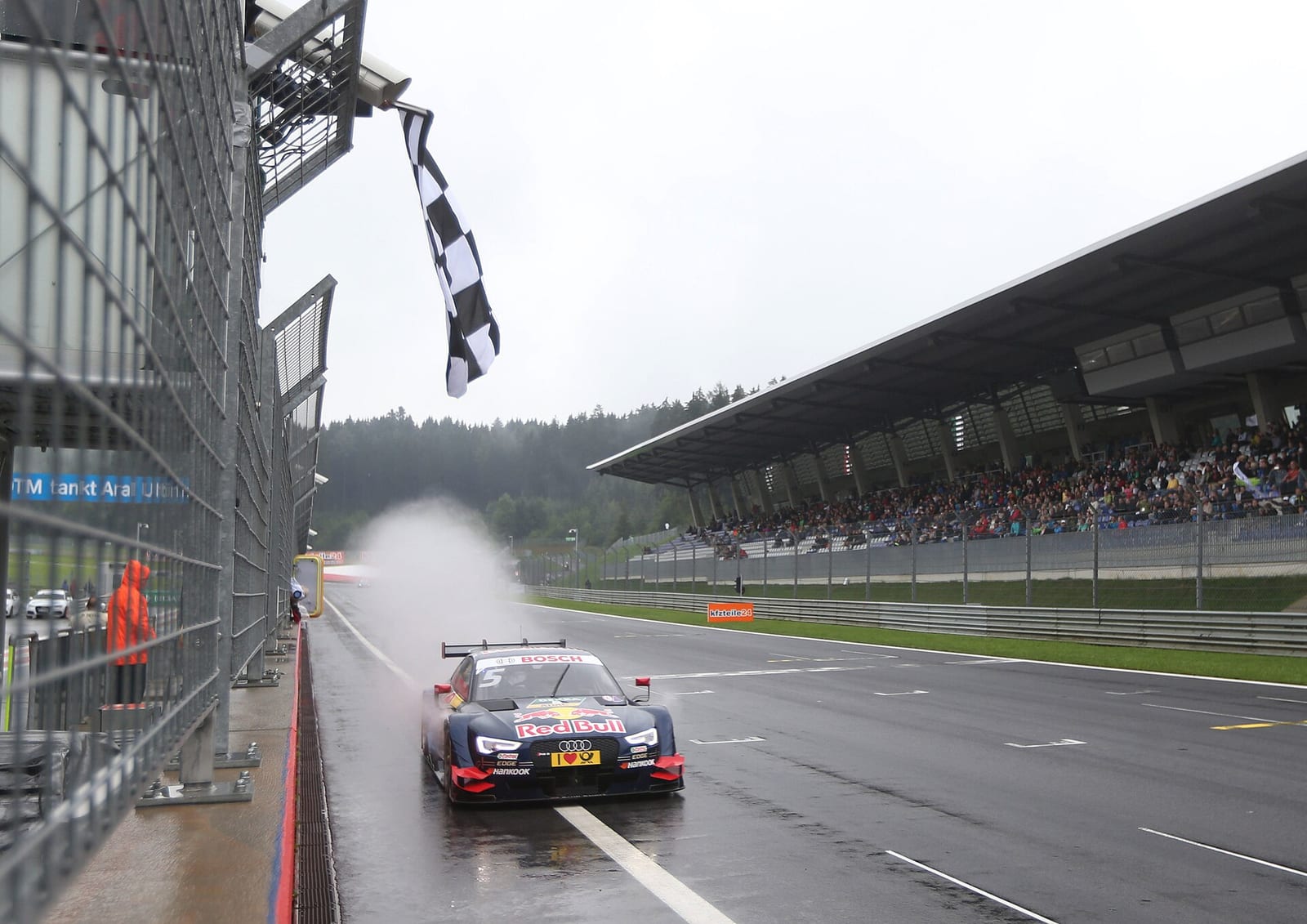 An Audi RS 5 DTM takes the chequered flag in the rain at the Red Bull Ring in 2015