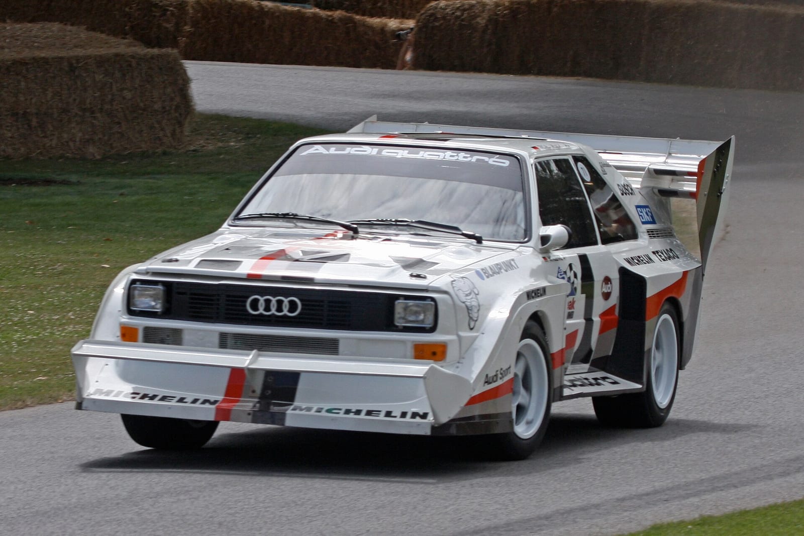 White Audi Sport quattro S1 Pikes Peak with large front and rear wings driving up a hill climb course
