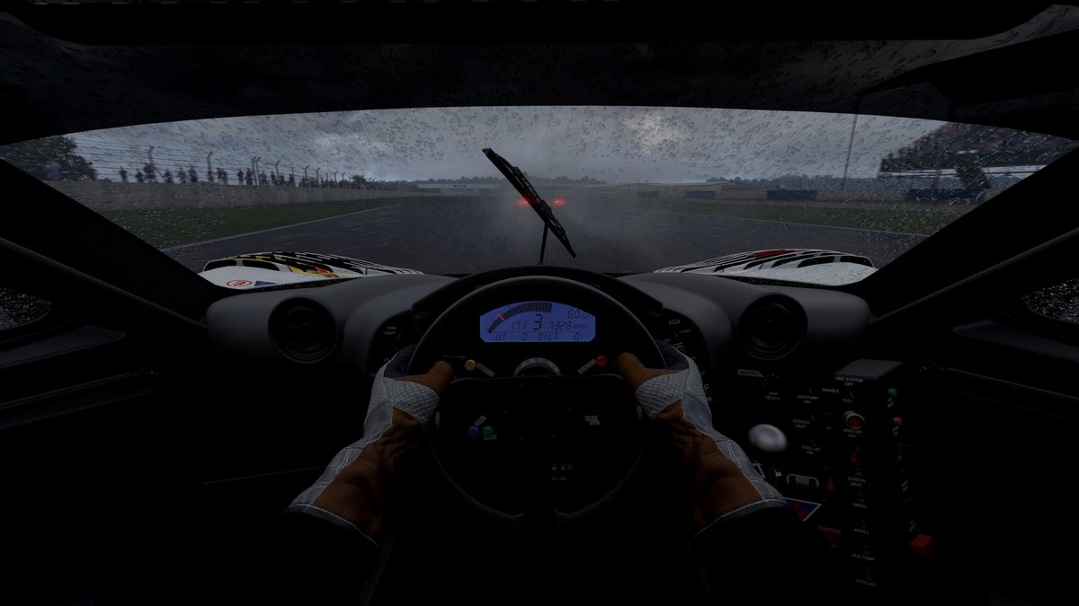 Cockpit view at night in the rain in Automobilista 2, with the driver's hands on the wheel and a wiper crossing the windscreen