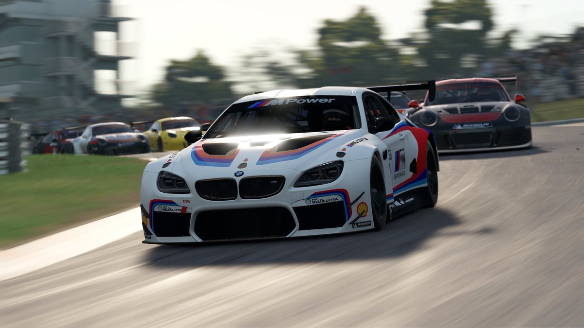 A BMW GT car in BMW Motorsport colours leads a pack of GT cars through a corner in daylight in Automobilista 2