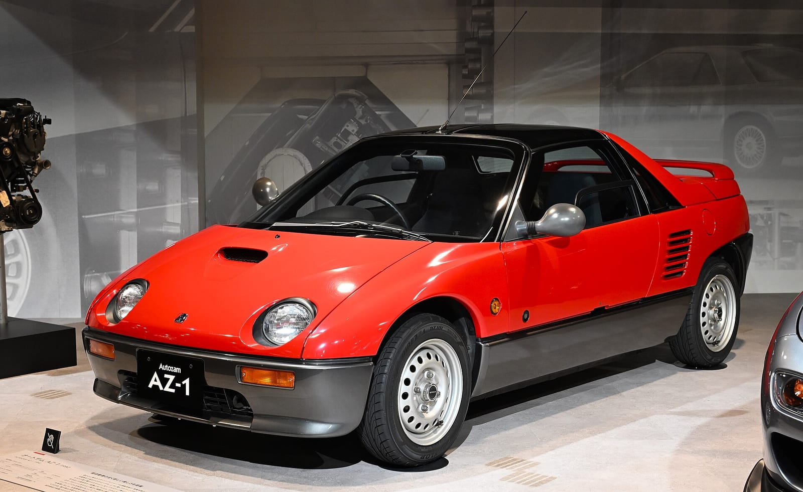 A red 1992 Autozam AZ-1 with gull wing doors on display in a museum