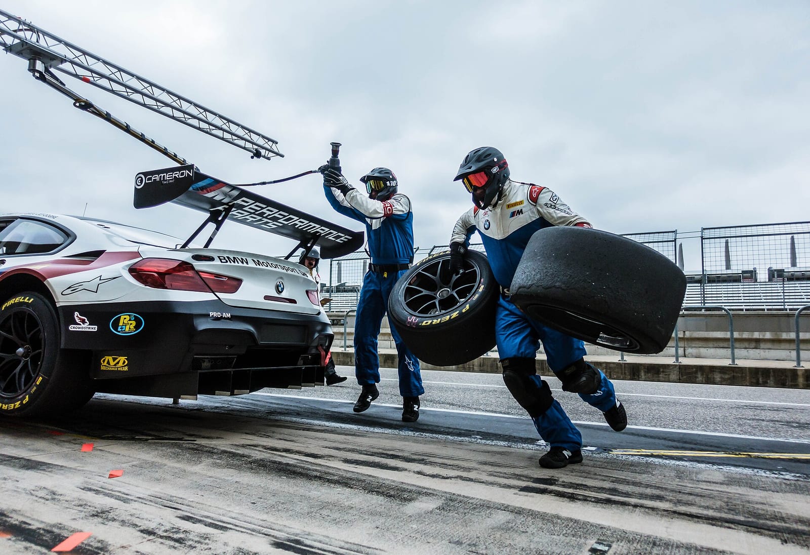 Mechanics carrying fresh tyres to a BMW M6 GT3 during a pit stop