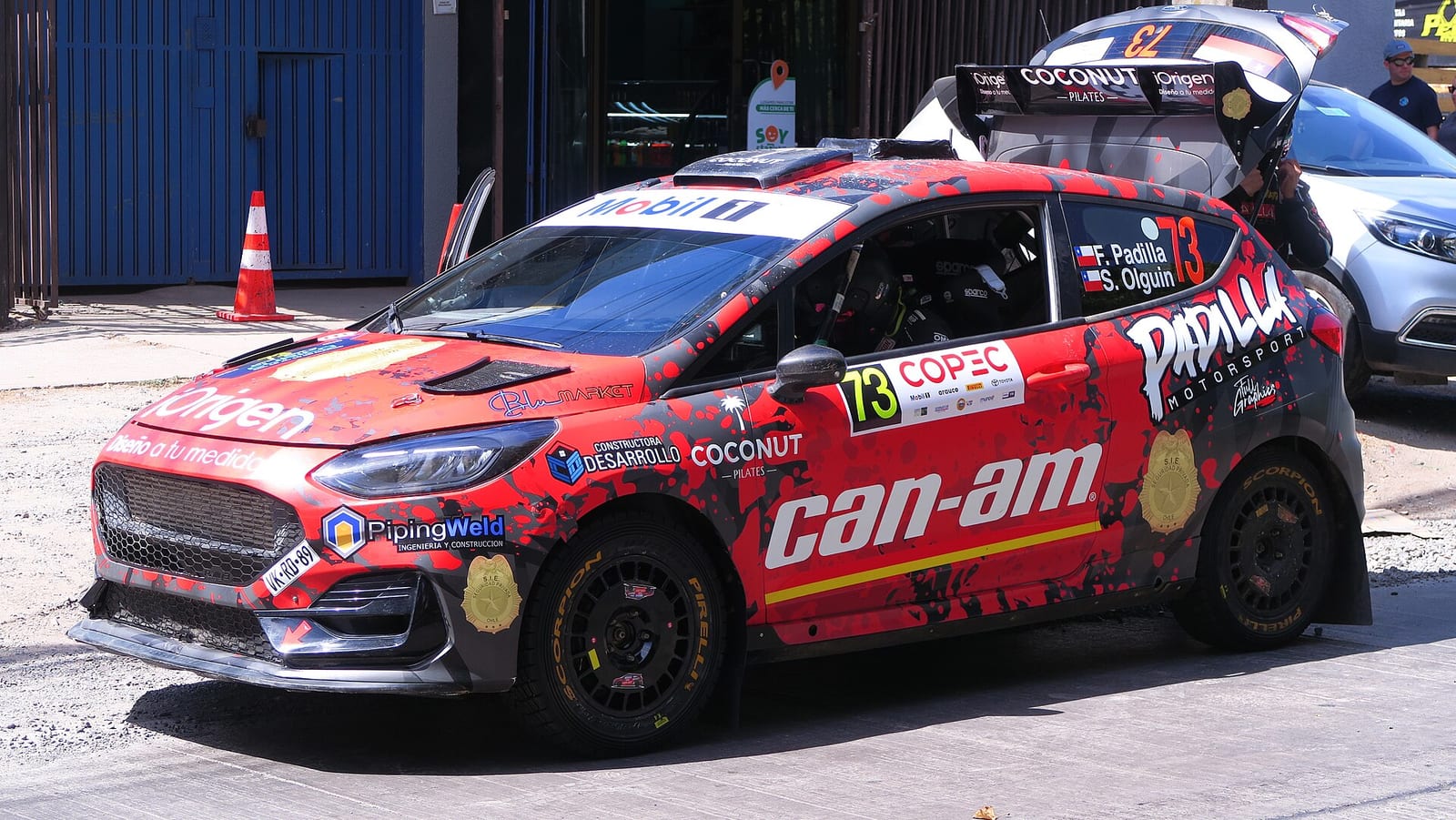 A red and black Ford Fiesta Rally3 parked in a service area
