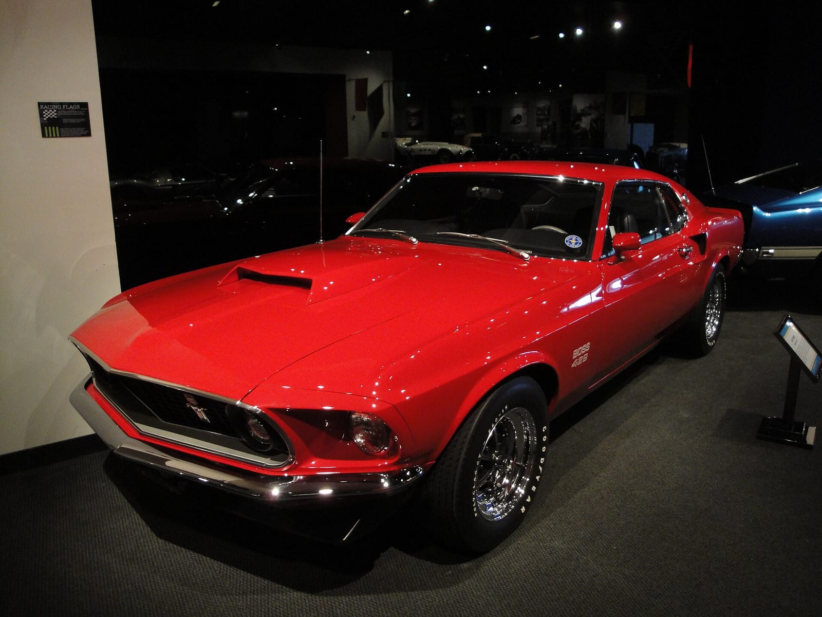 A red 1969 Ford Mustang Boss 429 in a dark museum hall