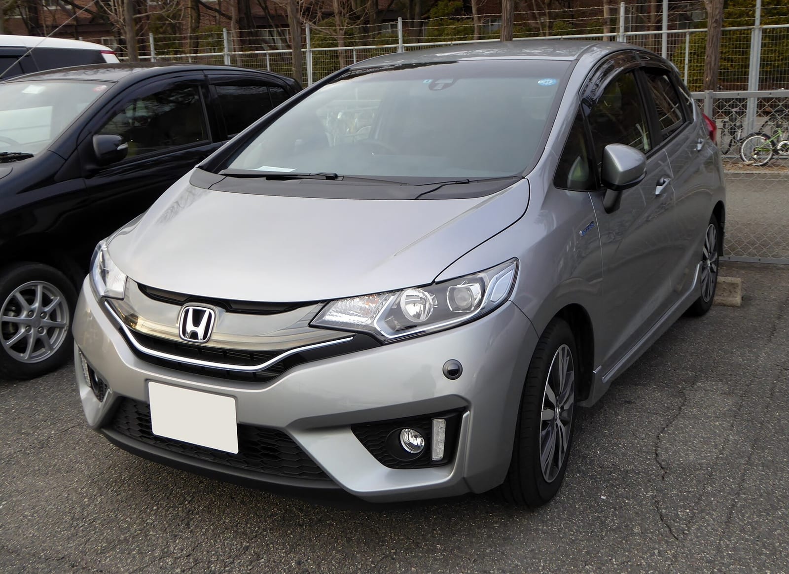 A silver Honda Fit Hybrid seen from the front in a car park