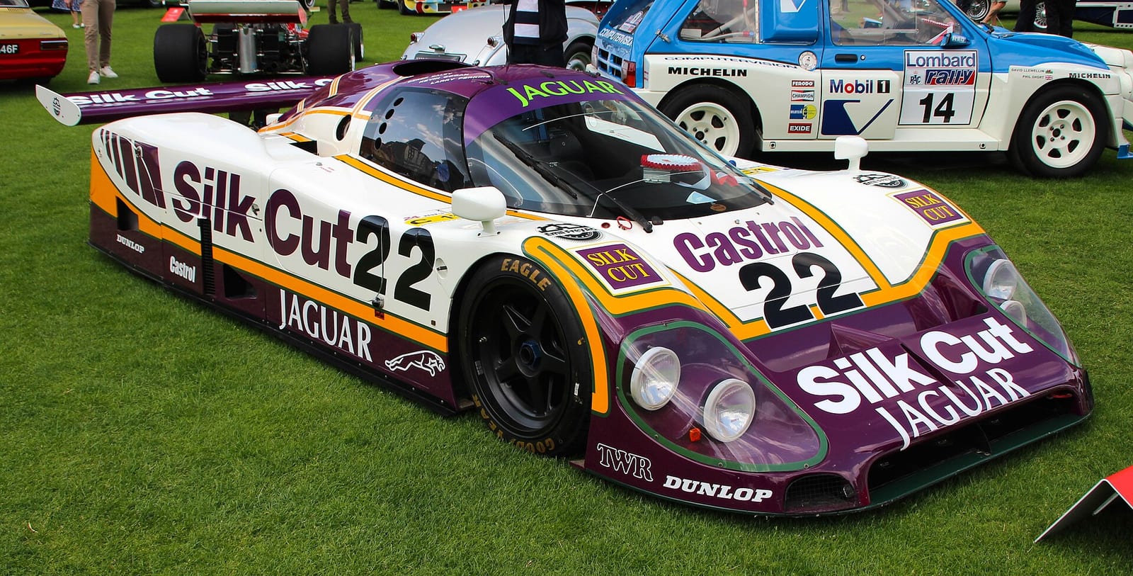 A Jaguar XJR-9 in purple, white and yellow livery with the number 22 on display on grass