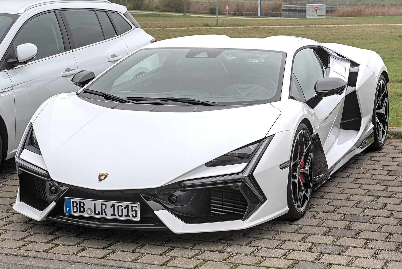 A white Lamborghini Revuelto parked on cobblestones