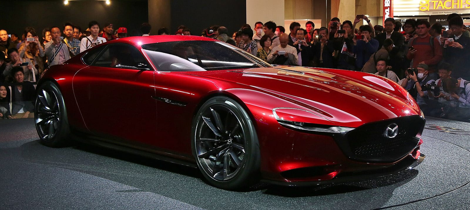 Red Mazda RX-Vision concept car on a show stand surrounded by a crowd