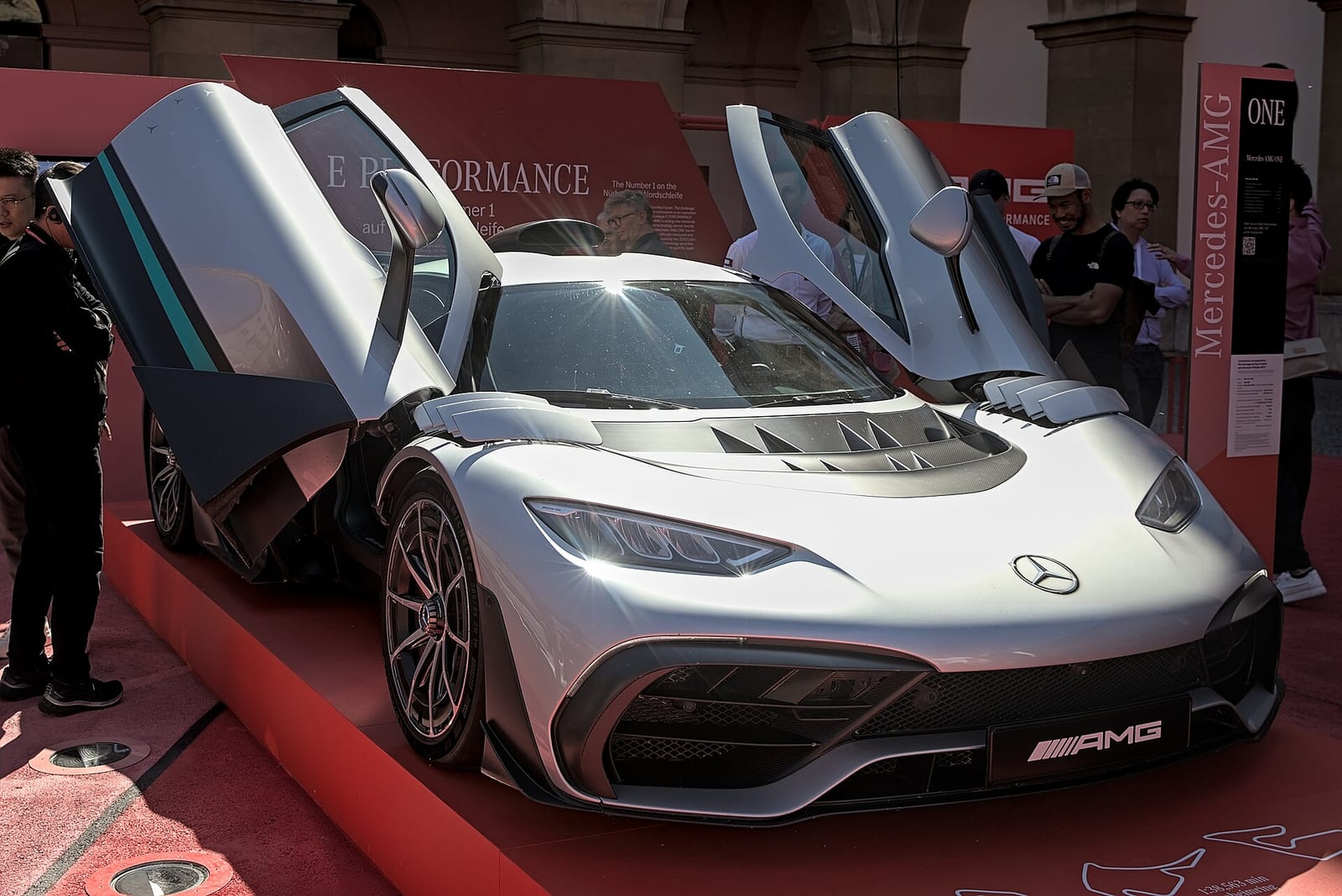A silver Mercedes-AMG ONE with its doors open at a motor show