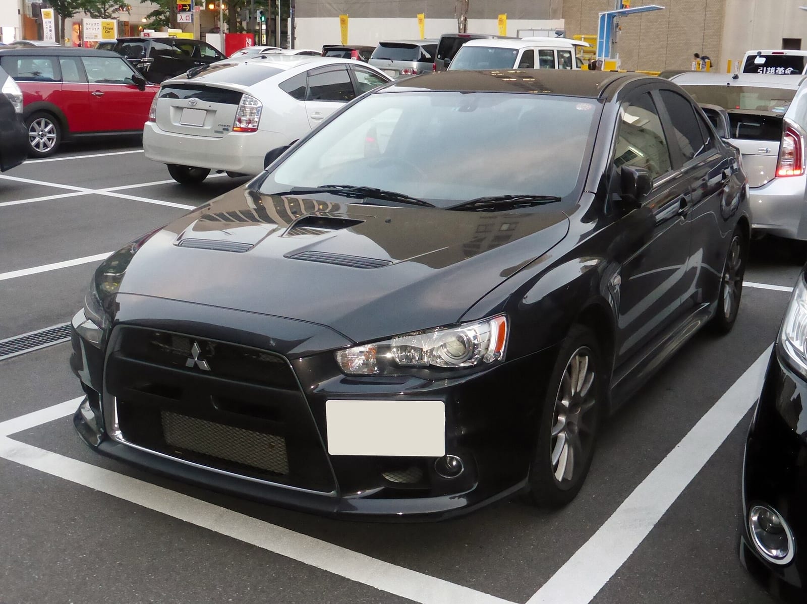A black Mitsubishi Lancer Evolution X GSR parked in a car park, front view