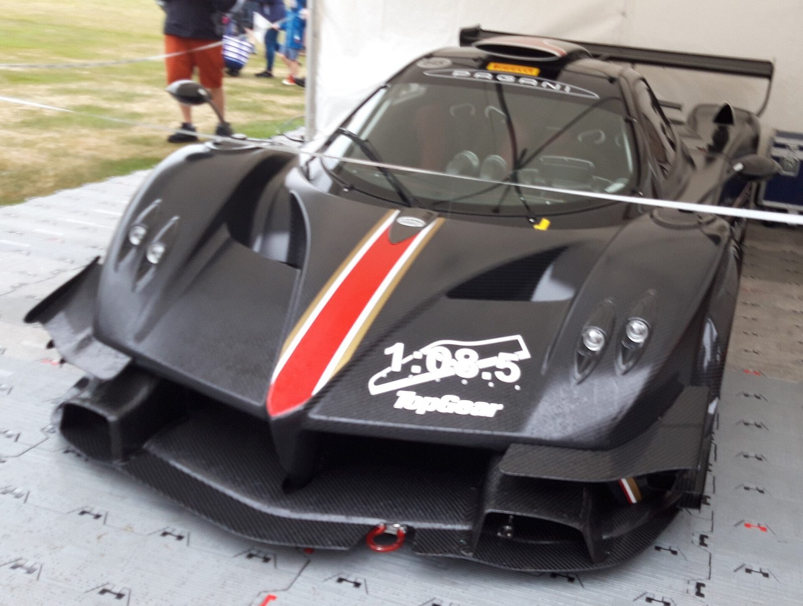 A black carbon Pagani Zonda R with a red stripe in a paddock