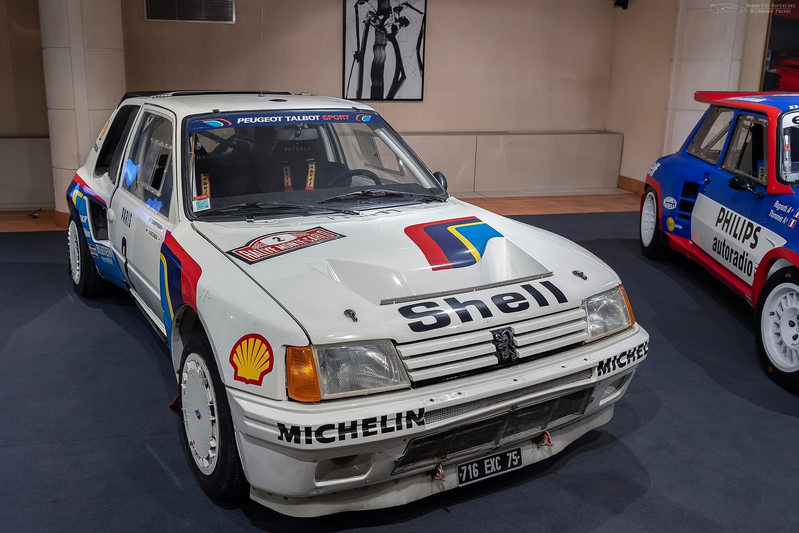 White Peugeot 205 Turbo 16 Group B rally car with Shell and Michelin logos in a museum
