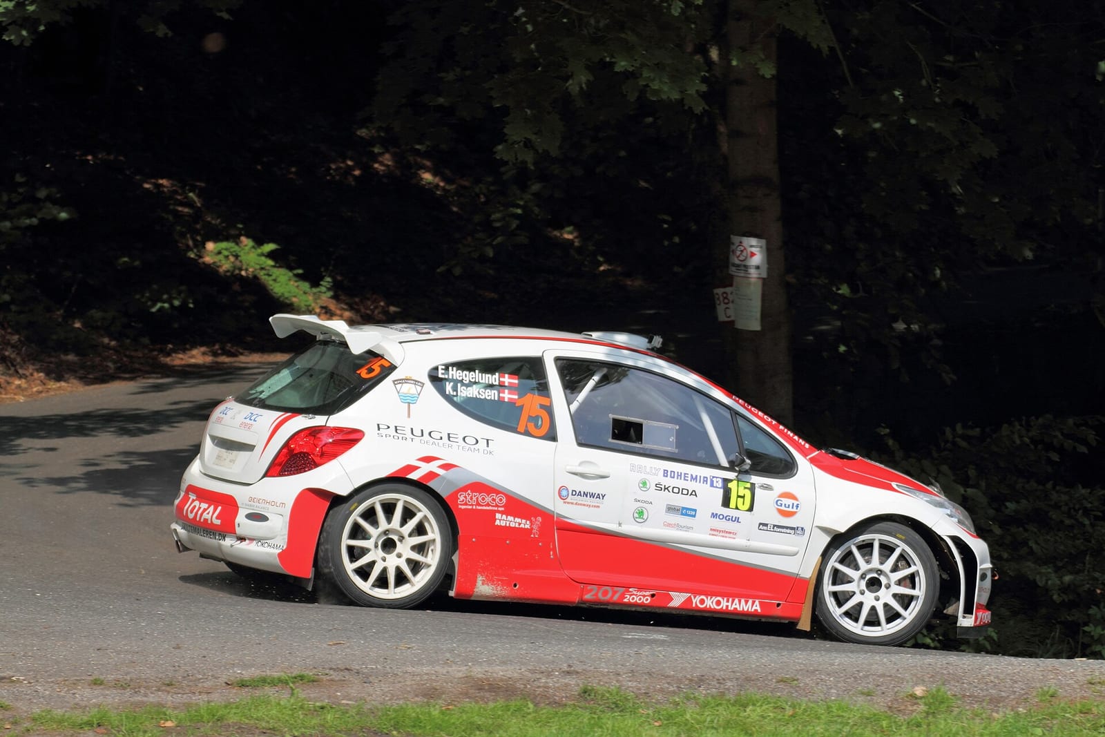A Peugeot 207 Super 2000 rally car on a tarmac stage