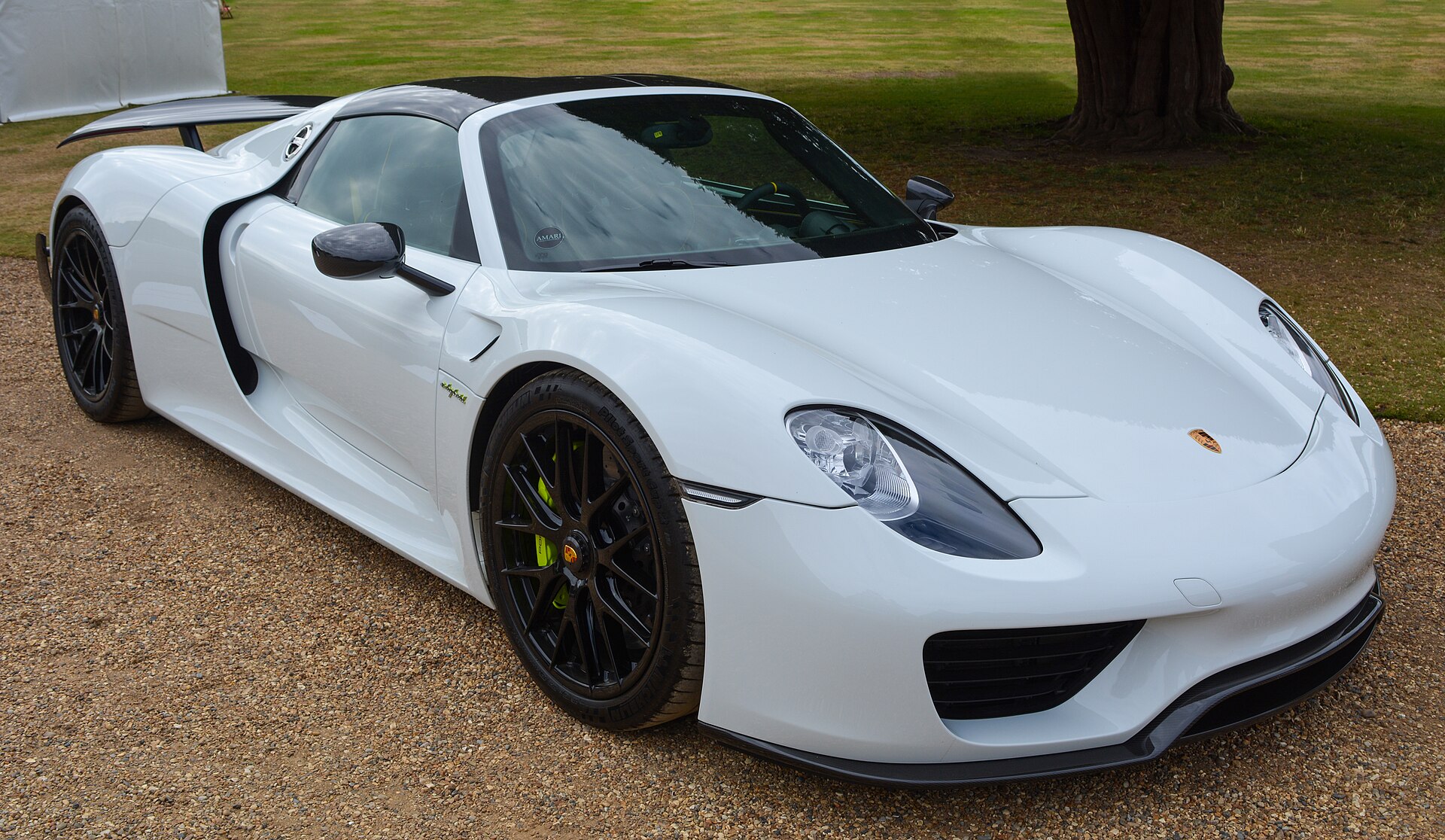 A white Porsche 918 Spyder parked on gravel