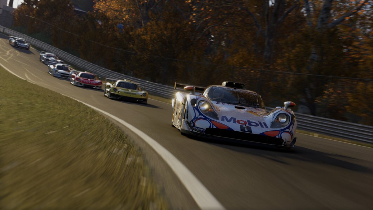 A Porsche 911 GT1-98 leads a line of GT1 cars through a fast corner in autumn light in Project Motor Racing