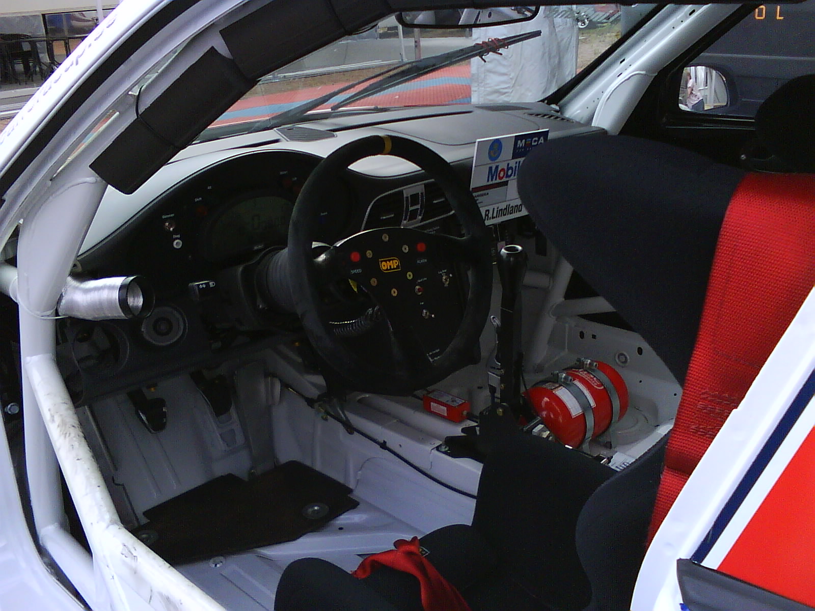 The cockpit of a Porsche Carrera Cup car with a bucket seat, a suede wheel close to the seat and a roll cage