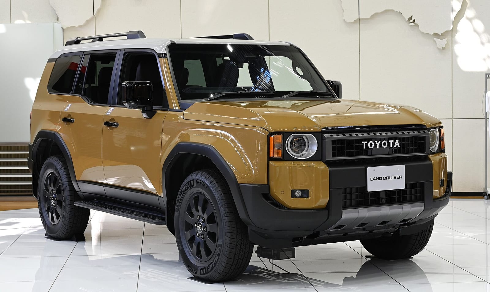A sand coloured Toyota Land Cruiser 250, front three quarter view