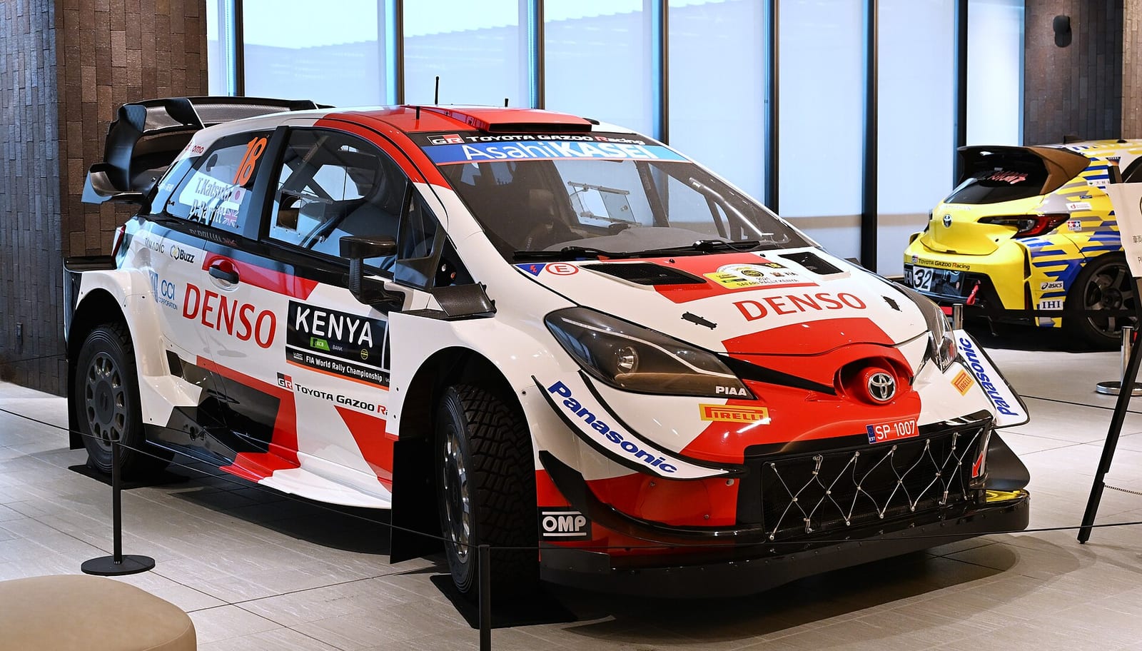 Toyota Yaris WRC in 2021 Toyota Gazoo Racing livery with number 18, displayed in a showroom