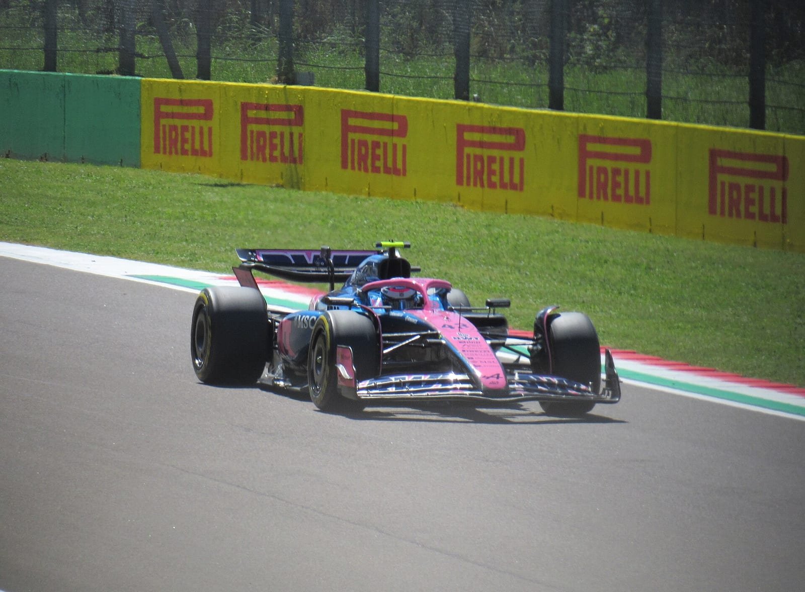 An Alpine A525 on track at Imola during the 2025 Emilia Romagna Grand Prix weekend, with the red, white and green kerb behind it