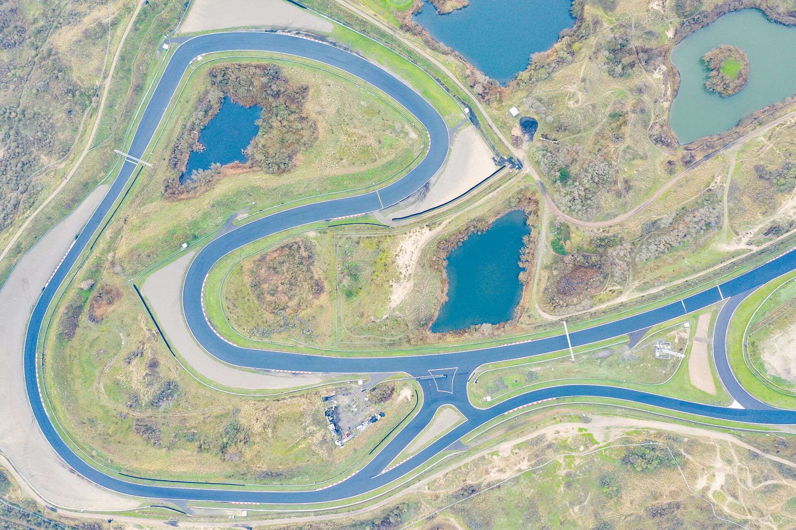 Aerial view of Circuit Zandvoort winding through the sand dunes on the Dutch coast, with small lakes inside the track