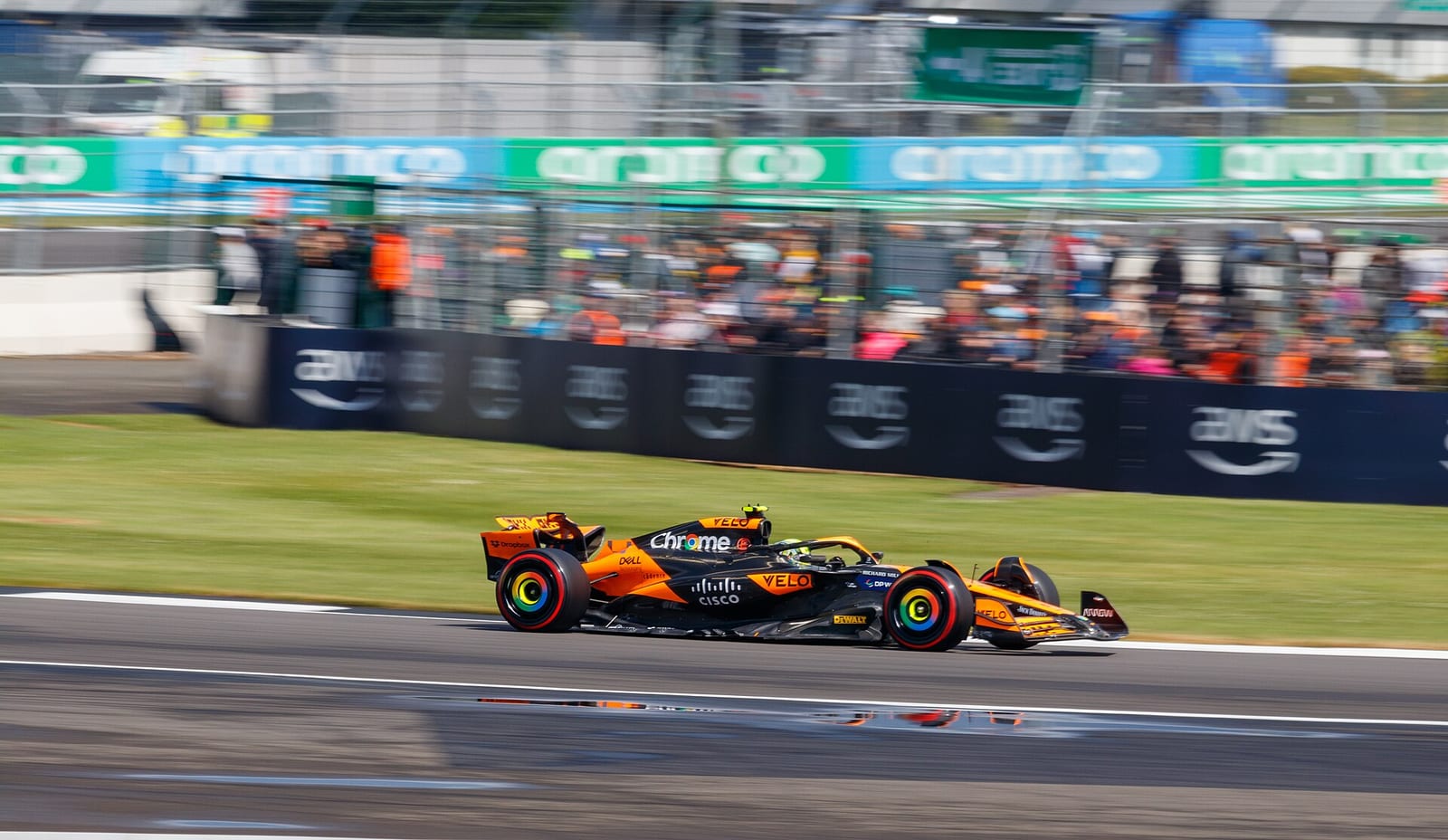 Lando Norris in the papaya McLaren MCL38 on soft tyres at Silverstone during the 2024 British Grand Prix weekend, with a full grandstand behind