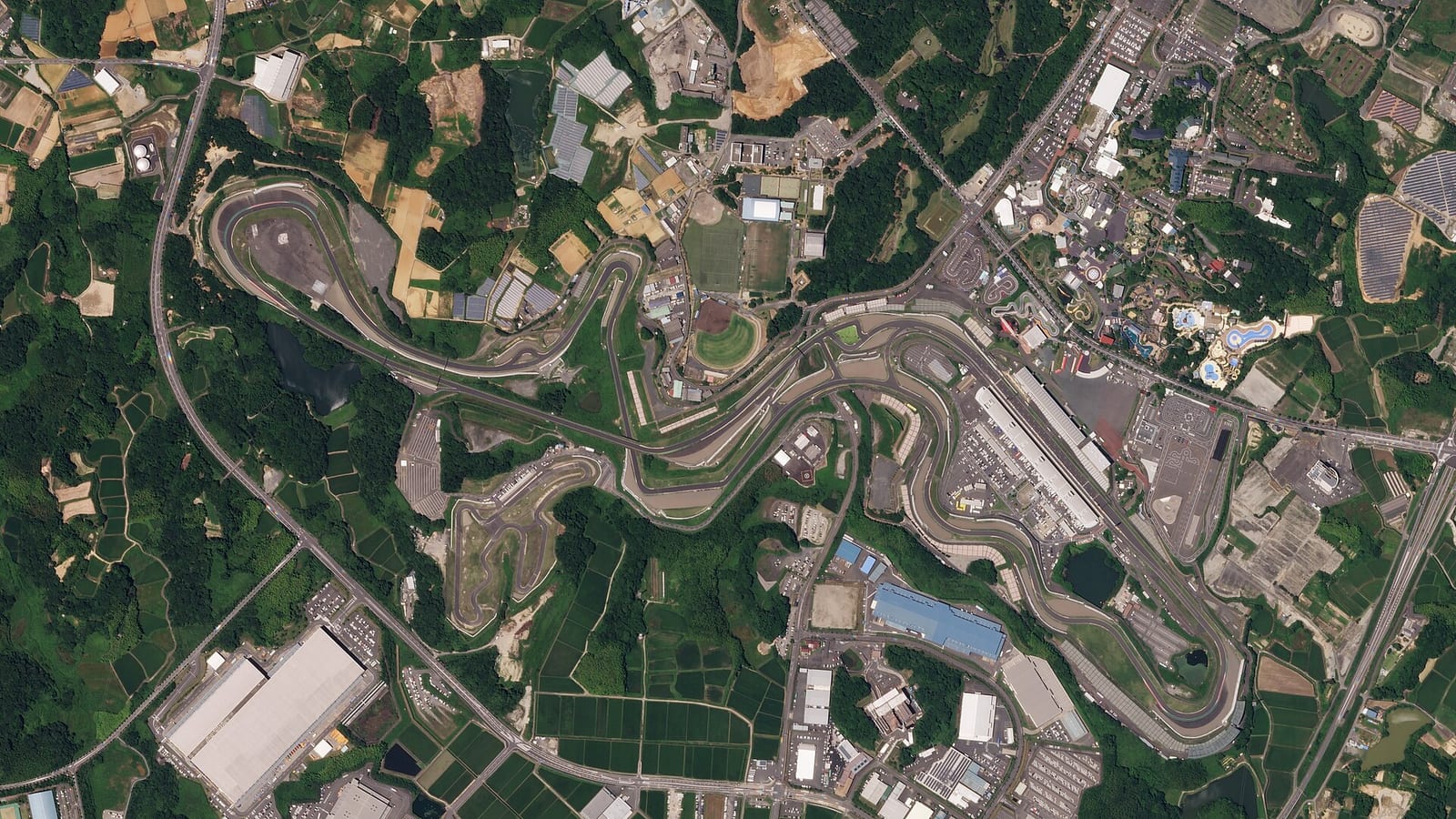Satellite view of the Suzuka circuit in Japan, showing the figure of eight layout with the crossover in the middle and the amusement park next to the pit straight