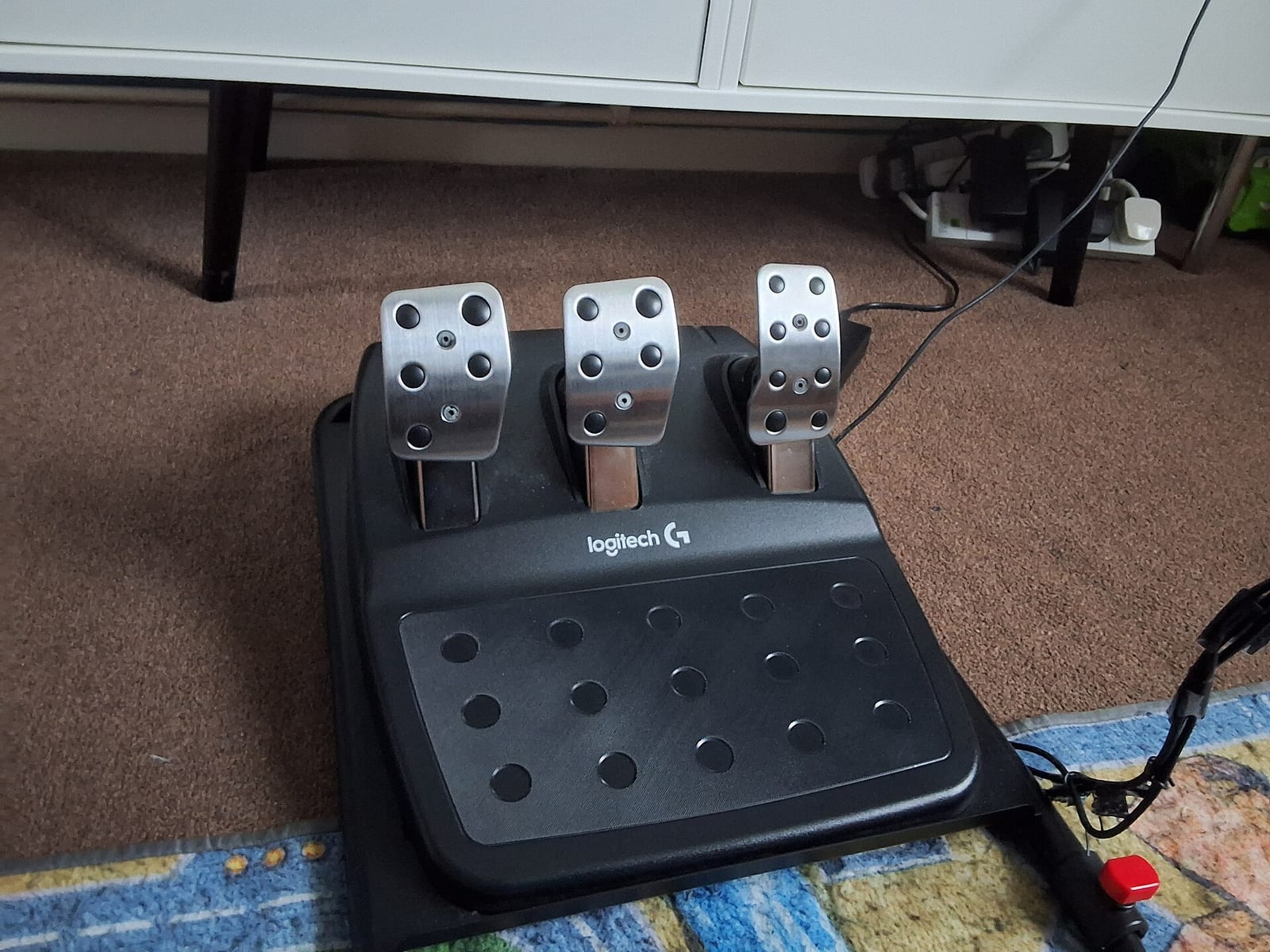 Logitech G29 and G920 three pedal set with steel pedal faces on a carpet floor
