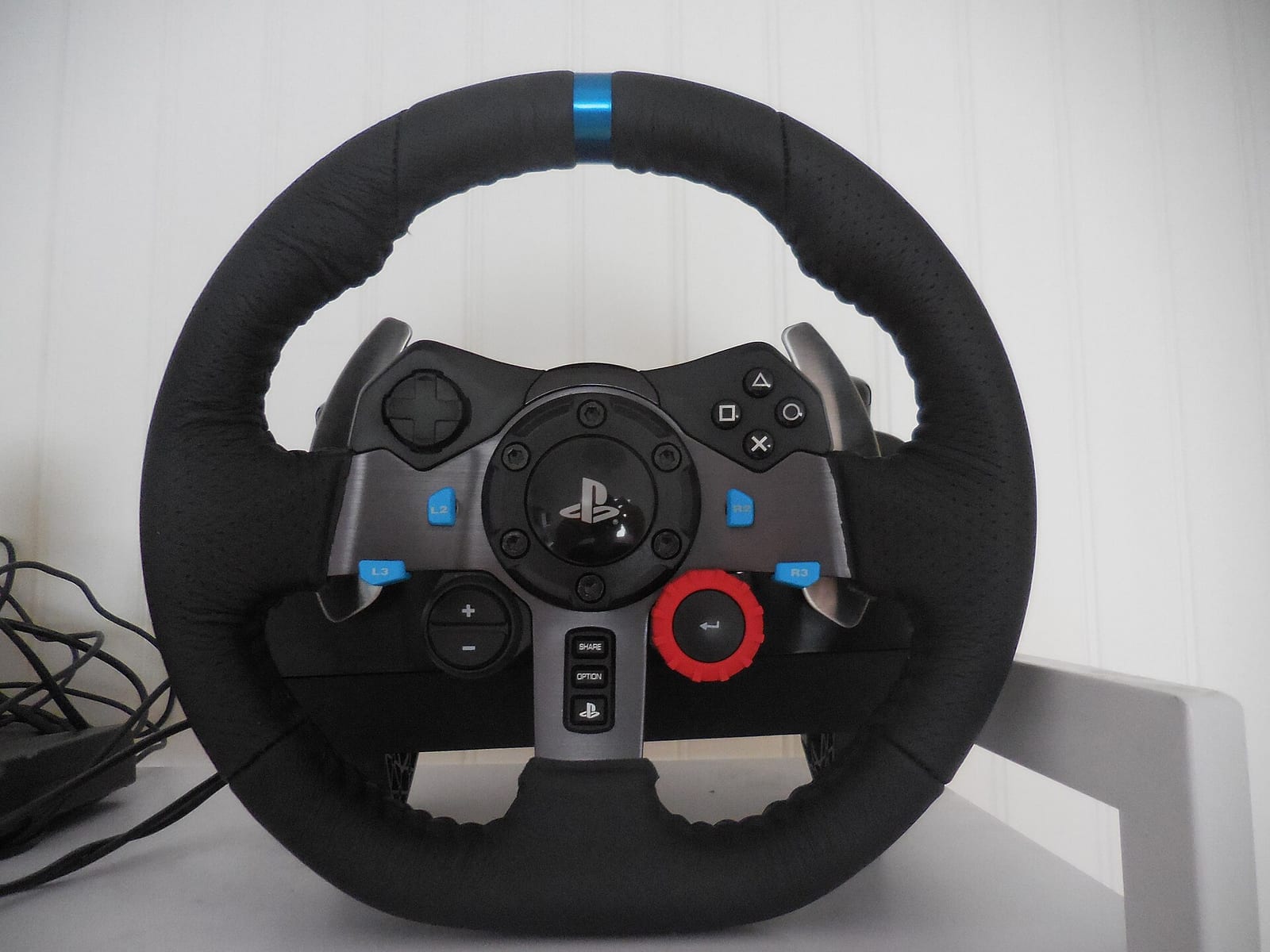 Logitech G29 steering wheel with PlayStation buttons, blue centre stripe and red rotary dial