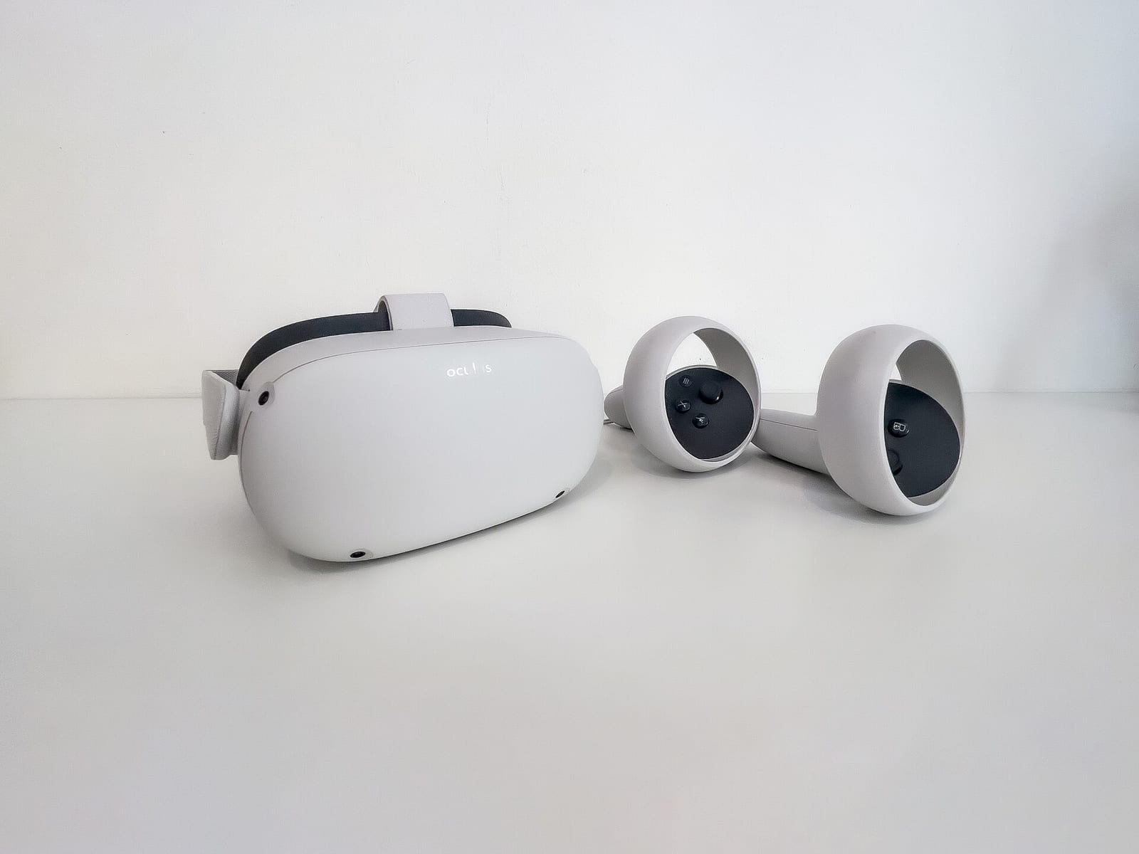An Oculus Quest 2 headset with its two controllers on a white table
