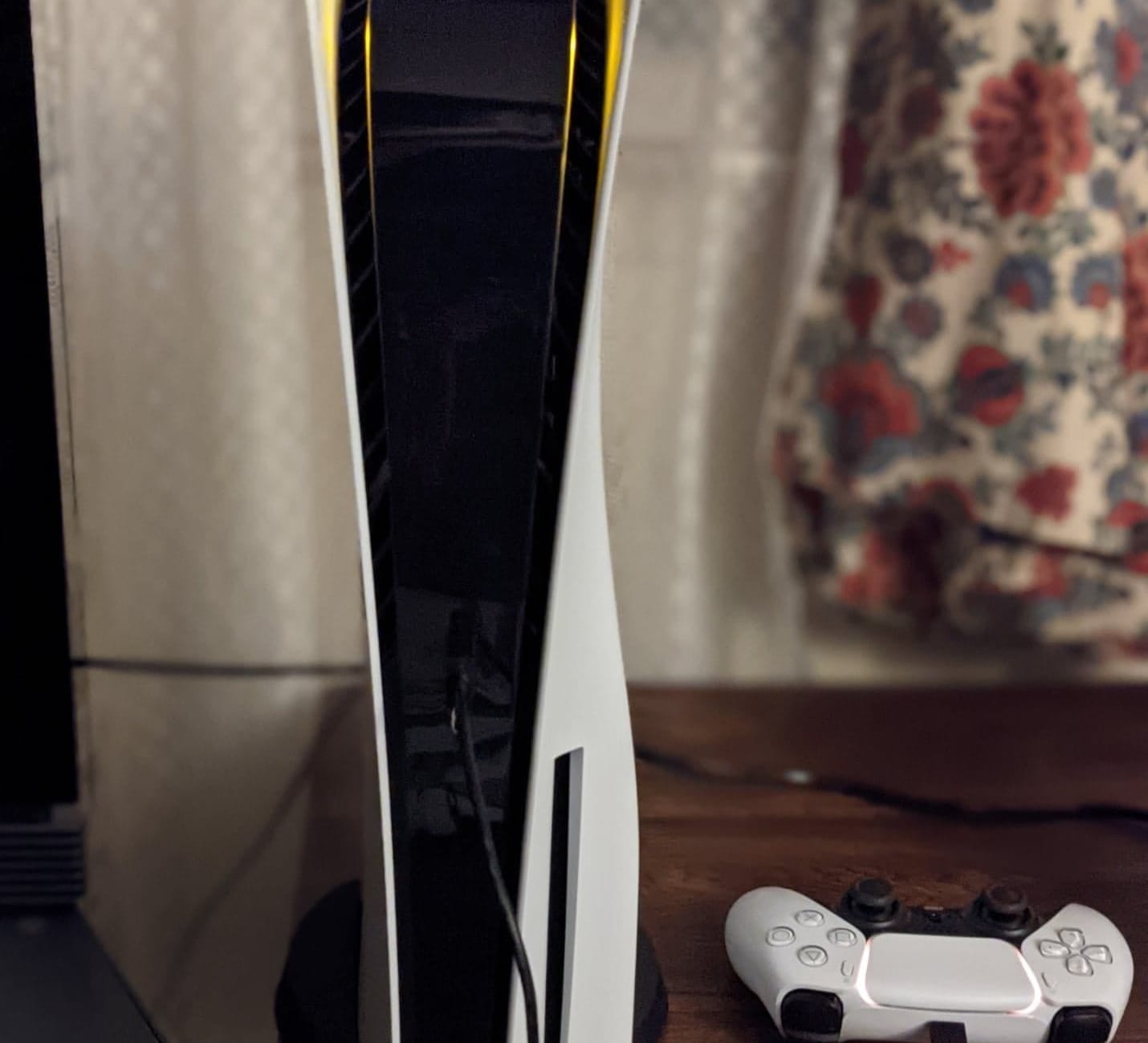 PlayStation 5 console standing upright next to a white DualSense controller