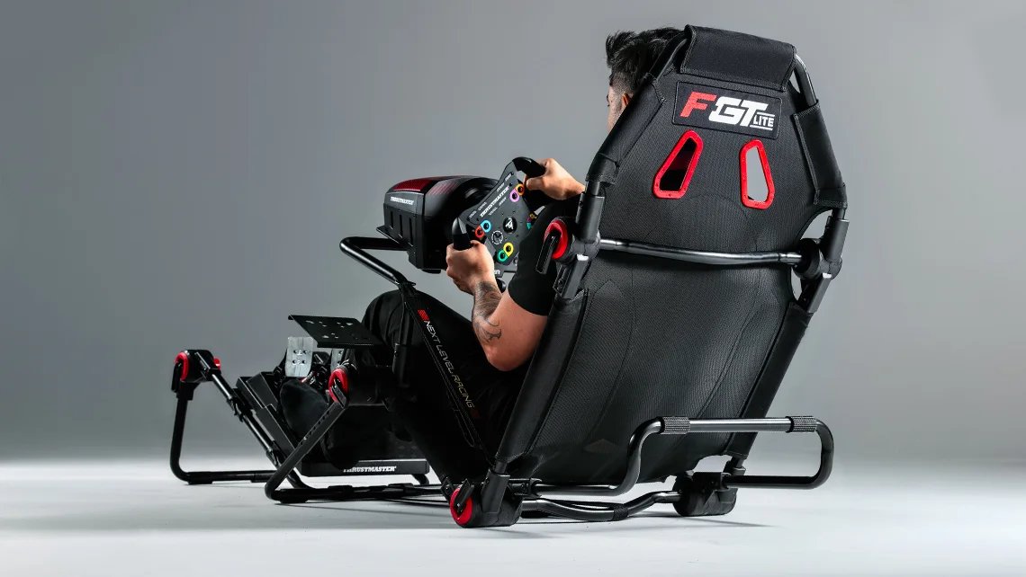 The Next Level Racing F-GT Lite folding cockpit with a wheel and pedals fitted and a driver in the seat