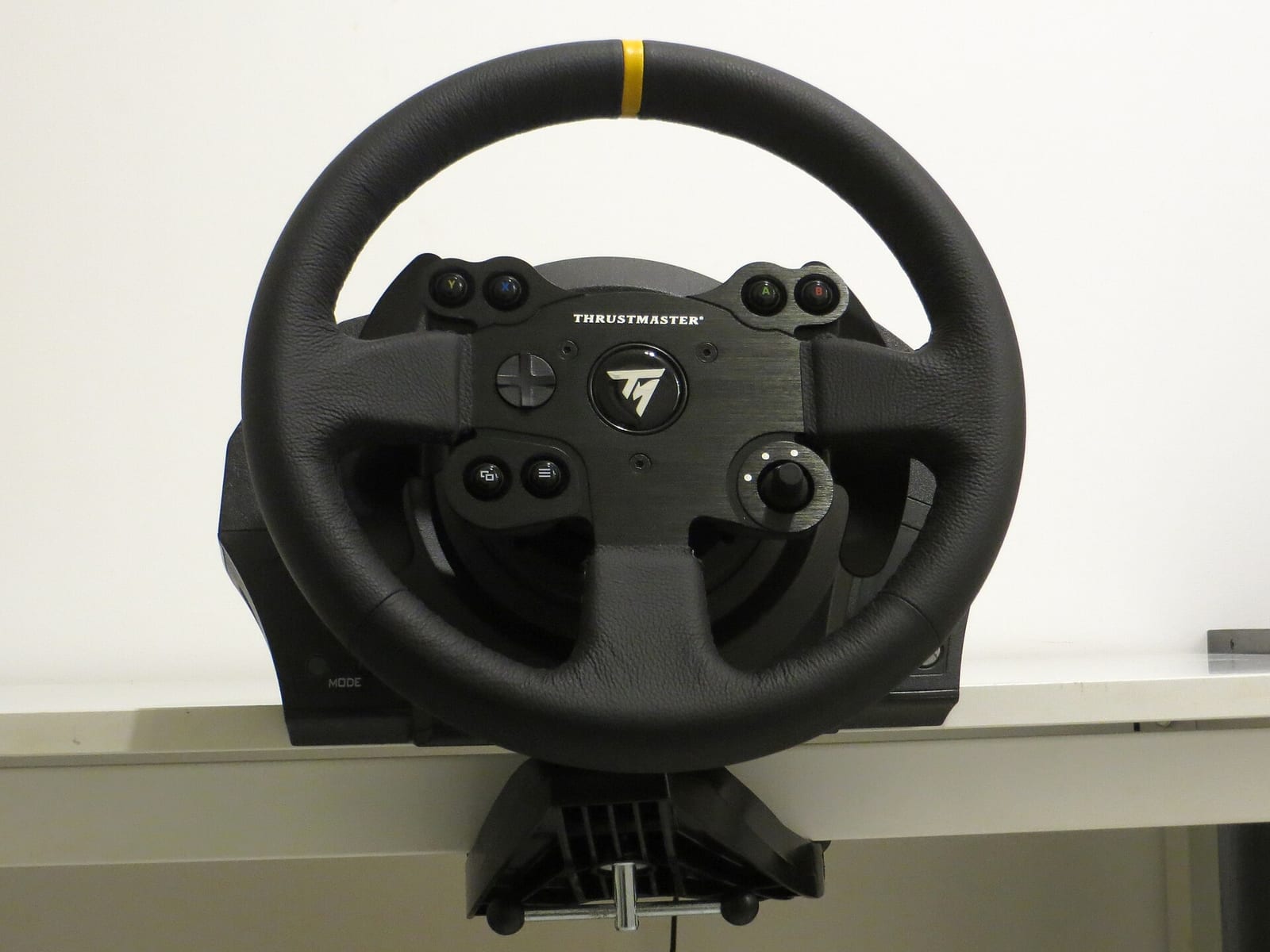 A Thrustmaster TX Racing Wheel Leather Edition seen from the front, clamped to a desk