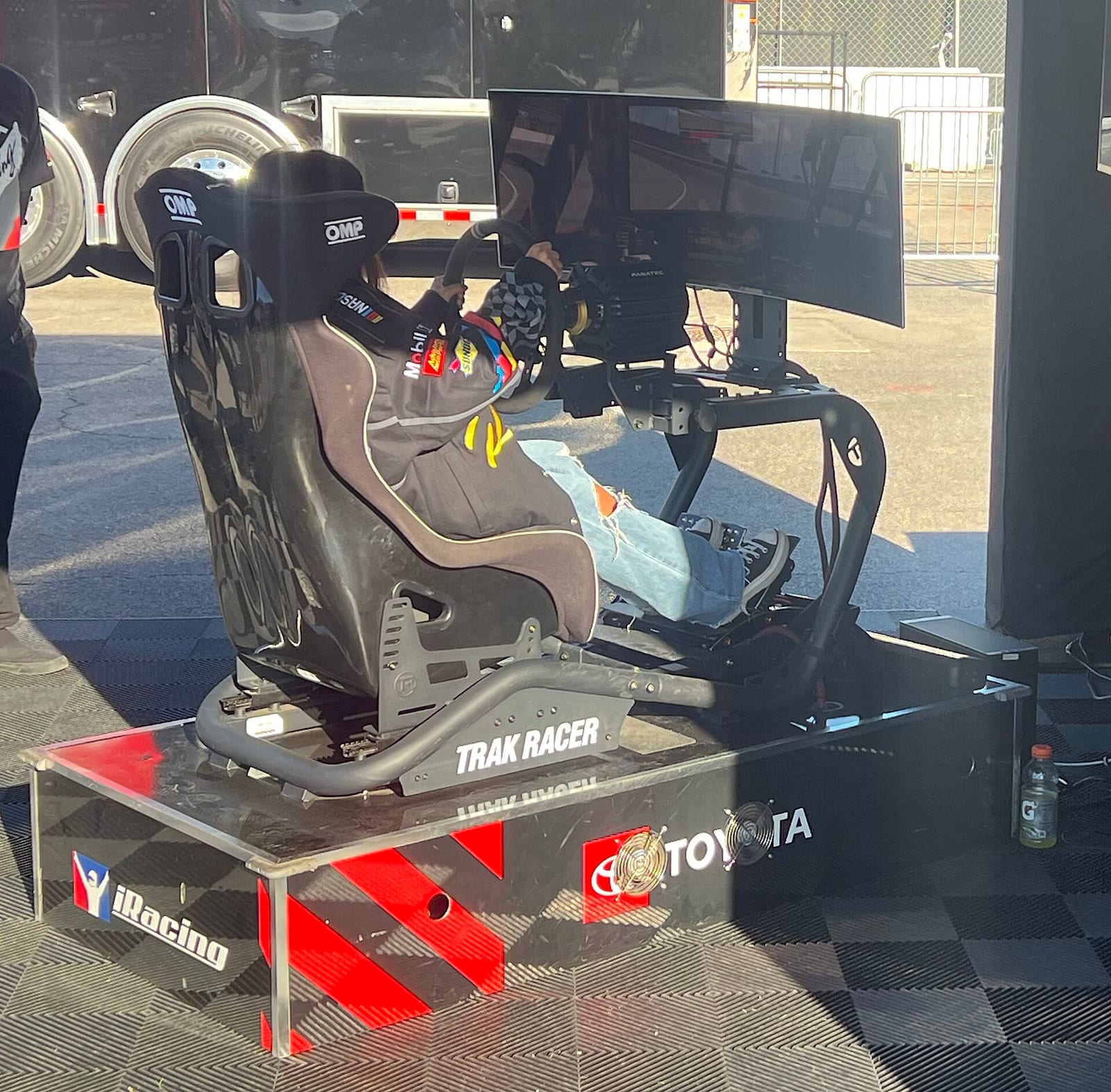 A sim racing rig with a seat, a wheel and a curved screen at a Toyota and iRacing display
