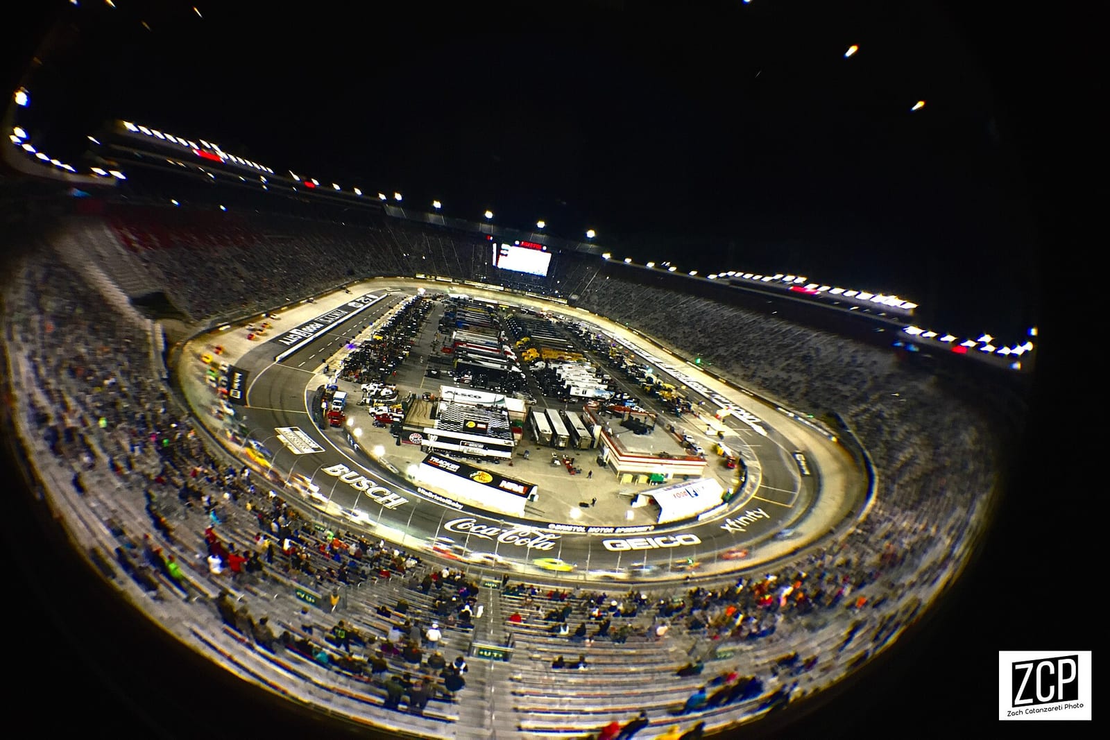 Bristol Motor Speedway at night from high in the grandstand, with the whole concrete oval and the cars on track