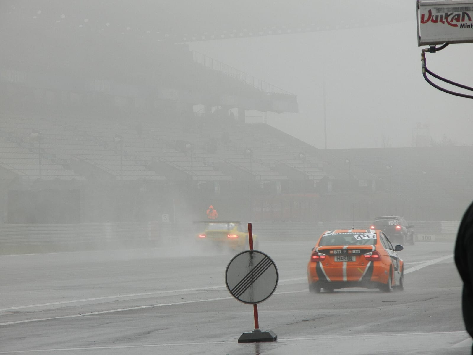 Cars on the pit straight at the Nurburgring in heavy rain and fog