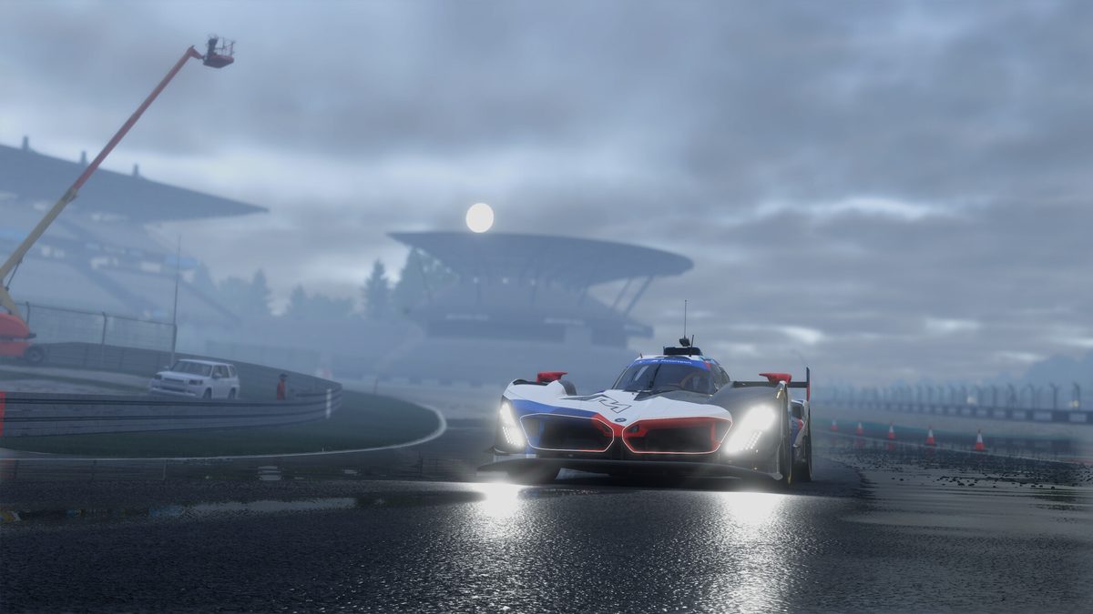 A Le Mans prototype with its lights on in the mist in Project Motor Racing, with a grandstand behind it