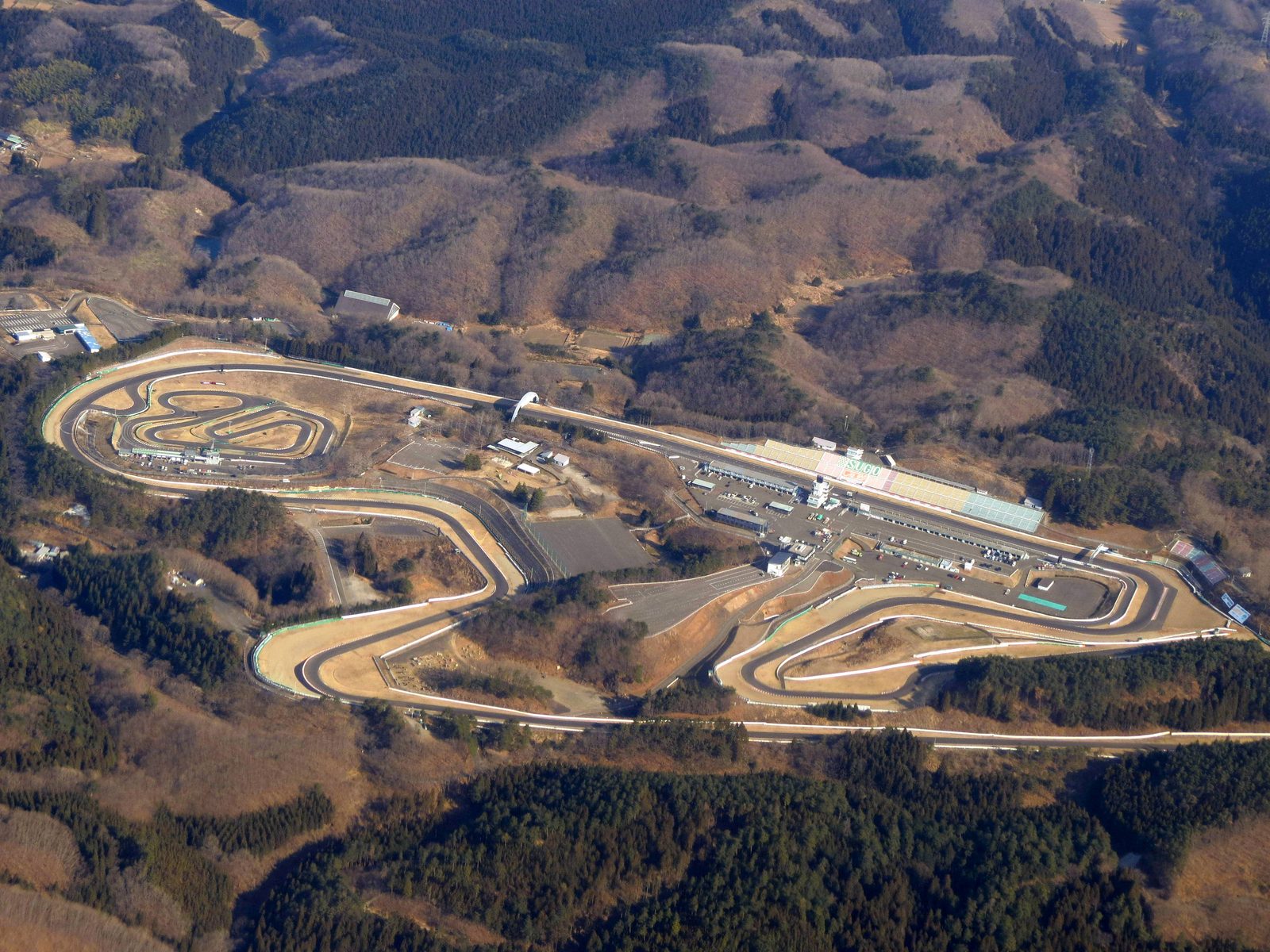 Aerial photo of Sportsland SUGO on its wooded hillside with the main straight, the grandstands and the infield loop